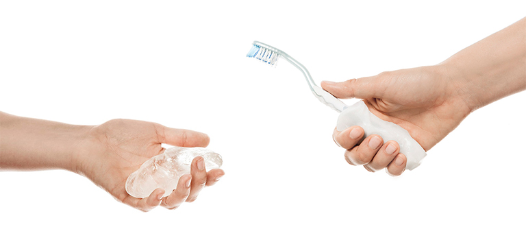 One hand holding combined Allfit and another hand holding a toothbrush with an Allfit grip
